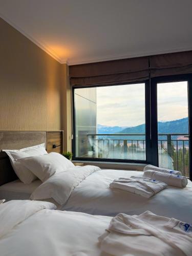 Dos camas en un dormitorio con una gran ventana. en Mountain Sky Hotel, 
