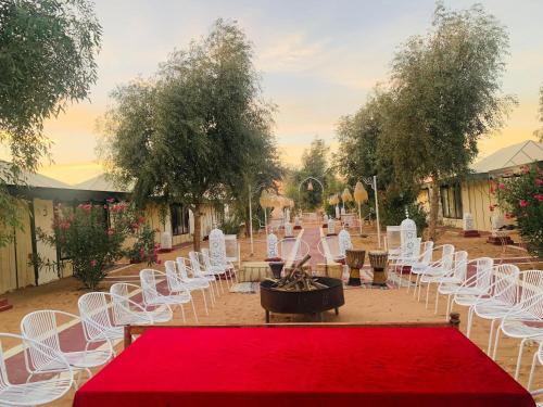 a room with white chairs and a red carpet and a table at Luxury Diaries Camp in Merzouga