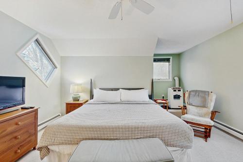 a bedroom with a bed and a tv and a chair at Newton Village 2B in Quechee