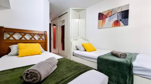 2 Betten in einem Zimmer mit gelben und grünen Kissen in der Unterkunft Cosme Velho: Luxo e Piscina para 8 Pessoas in Rio de Janeiro