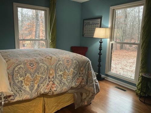 a bedroom with a bed and two windows at Quiet Forest Vacation home on a Private Road with Spacious Patios, Fire pit, Pet friendly and a Private pool in Tullahoma