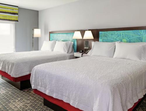 een hotelkamer met twee bedden met witte lakens bij Hampton Inn & Suites Cadillac in Cadillac