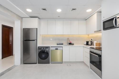 a kitchen with white cabinets and a washer and dryer at Ultimate Stay - Modern 1BR with City View Rooftop Pool Access in Dubai
