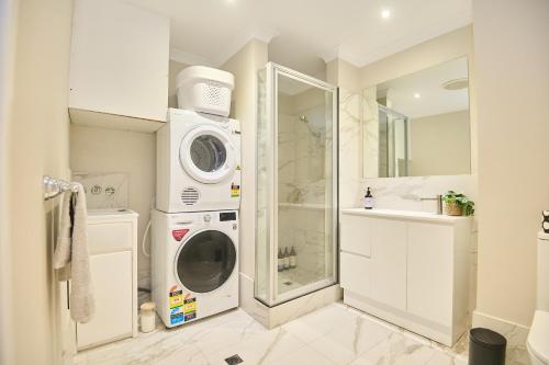 a bathroom with a washing machine and a sink at Central Perth Apartment with Pool in Perth