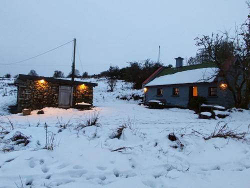 Mountain Cottage with Barn Sauna, Clonbur, Galway في Clonbur: كابينة في الثلج عليها انارة