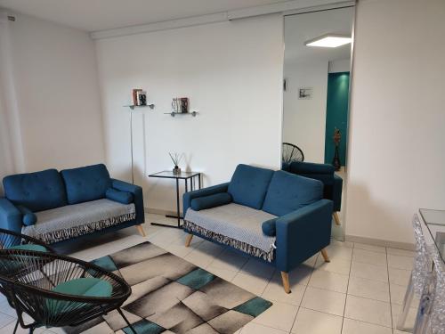 a living room with a blue couch and a chair at Appartement 2 terrasses face mer de 100m2 in Saint-Florent