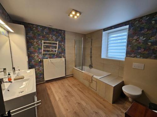 een badkamer met een wastafel, een bad en een toilet bij le Lombry in Aywaille