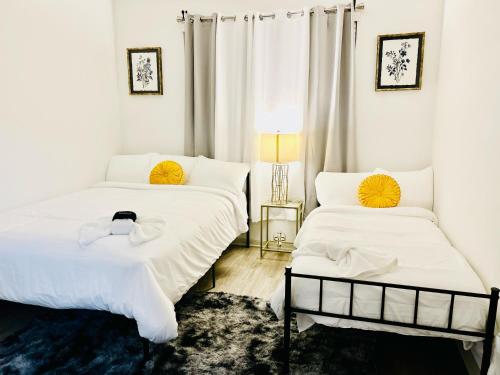 a bedroom with two beds with white sheets and a lamp at Cozy & Chic Frisco Scape in Frisco
