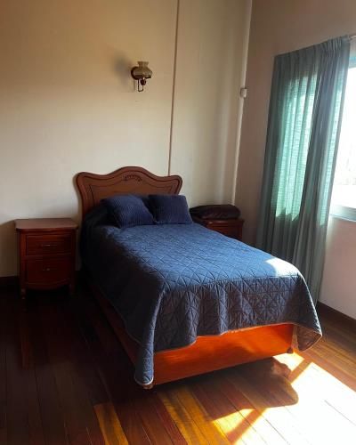 a bedroom with a bed with a blue blanket and a window at Casa Carmesí in Oaxaca City