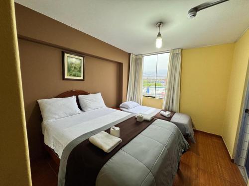 a hotel room with two beds and a window at La Posada del Rey - Lima Airport Hostel in Lima