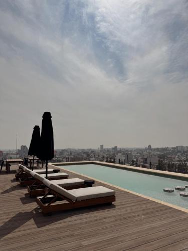 a swimming pool with chaise lounges and umbrellas on the roof at Luxury Penthouse Loft en Piso 29, Zona Norte in Miravalle