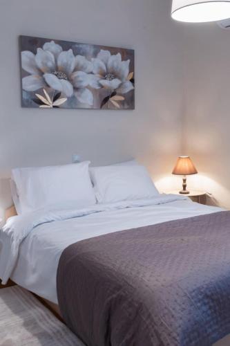 a bedroom with a bed with a painting on the wall at Lithaia Aura-Trikala in Pýrgos