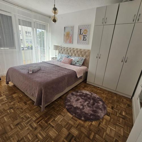 a bedroom with a bed with white cabinets and a rug at FRIENDLY HOME in Tuzla