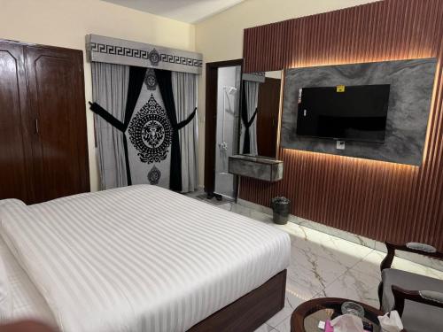 a bedroom with a bed and a flat screen tv at Royal Continental DHA Karachi in Karachi