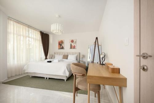 Executive Suite - Estia Premium Apartments في سلانيك: غرفة نوم بيضاء مع سرير ومكتب وطاولة