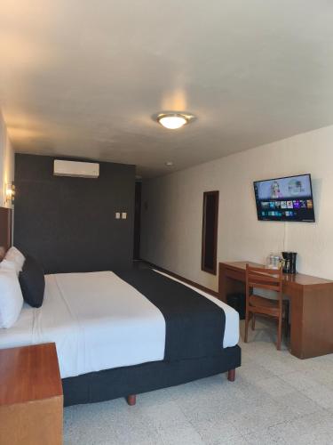 a bedroom with a bed and a desk and a tv at Hotel Central in Veracruz
