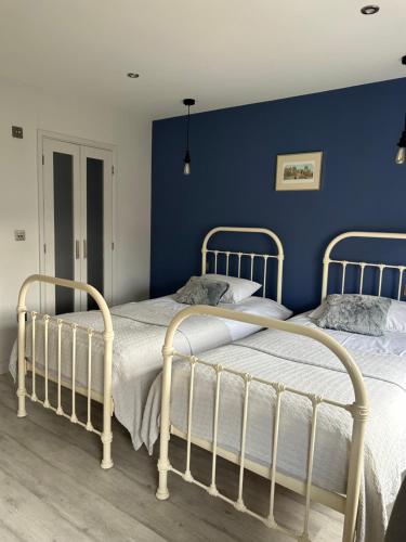 two beds in a bedroom with a blue wall at Meadow Cottage Cambridge in Trumpington