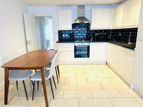 een keuken met een houten tafel en witte kasten bij Westferry Deluxe Apartment 3 in Londen