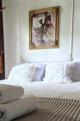 a white bed with a painting on the wall at Mangoré Rústico Cabaña 1 in La Granja