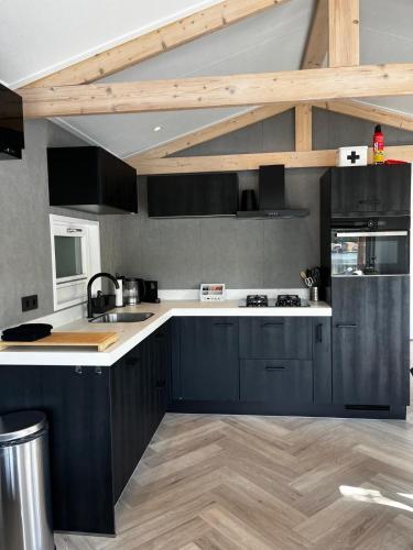 a kitchen with black cabinets and a white counter top at Luxe nieuwbouw chalet aan het water in Hoevelaken