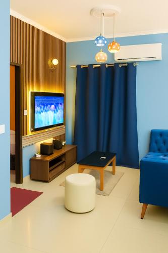 a living room with a blue curtain and a tv at Loïc Appart in Douala