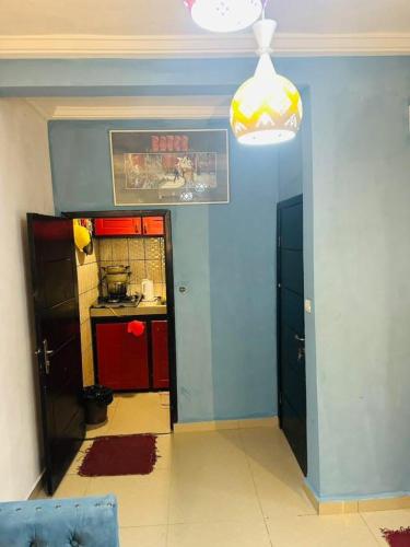 a room with a kitchen with a blue wall at Loïc Appart in Douala