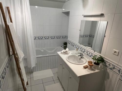 a white bathroom with a sink and a tub at gîte La Maison d'Odette in Saint-Rémy-du-Plein
