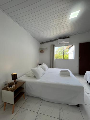a white bedroom with a large bed and a window at Flor do Mar - Hospedaria in Santa Cruz
