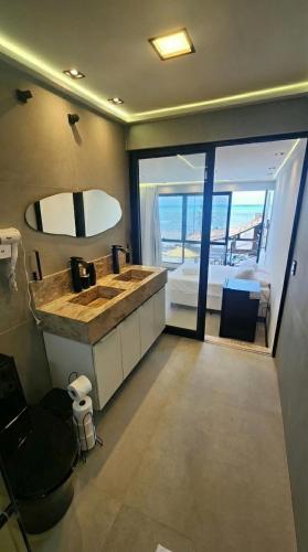 a bathroom with a large sink and a bedroom at Mirassol Flats in Natal