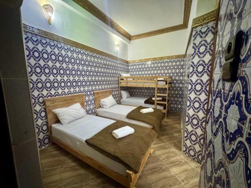 two beds in a room with blue and white tiles at Riad al anwar in Rabat