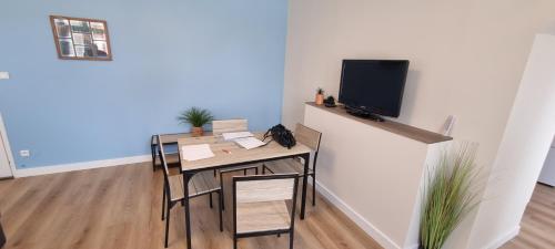 Habitación con mesa con sillas y TV. en Appartement proche Grand Parc 1 Chambre, en Mauléon