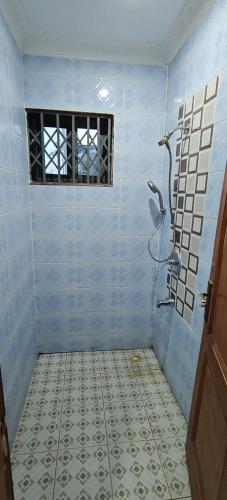 a blue tiled bathroom with a shower with a window at Purple Springs Elmina Suite #3 in Esamang