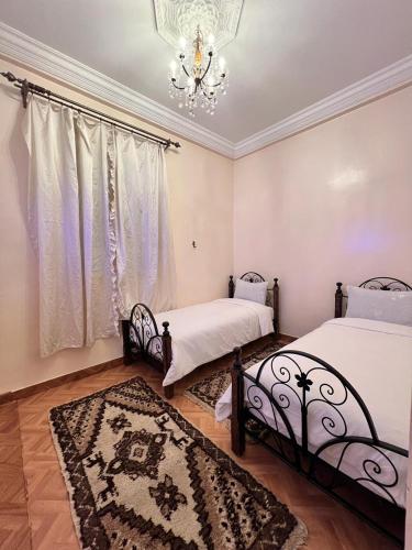 a bedroom with two beds and a chandelier at Tumsilt in Marrakesh