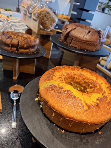 ibis Pelotas في بيلوتاس: ثلاث كعكات موجودة على الأطباق على طاولة