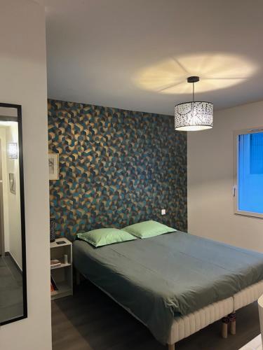 1 dormitorio con 1 cama y pared cubierta de papel pintado en Chez Olivier et Damien, en La Roche-sur-Yon