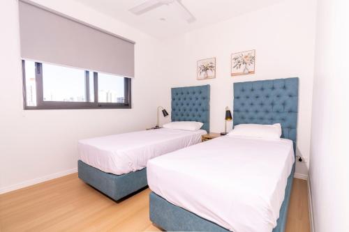 two beds in a room with white walls at Boutique Apartments Southport in Gold Coast