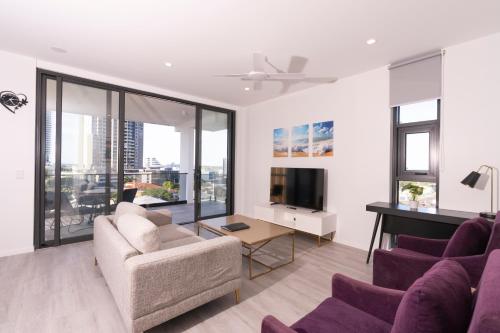 a living room with purple chairs and a tv at Boutique Apartments Southport in Gold Coast