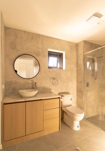 a bathroom with a sink and a toilet and a mirror at Boutique Apartments Southport in Gold Coast