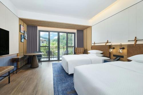 a hotel room with two beds and a flat screen tv at Four Points by Sheraton Anshun, Huangguoshu in Anshun