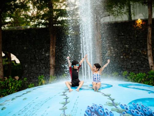 a boy and a girl sitting on top of a fountain at SO/ Sofitel Hua Hin in Cha Am