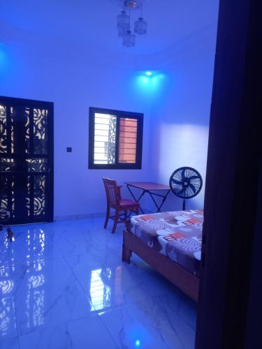 Femi في Keur Massar: غرفة بها سرير وطاولة وأضواء زرقاء