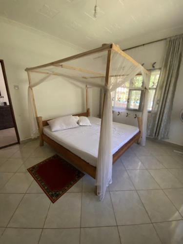 un letto con baldacchino in una stanza di Villa Soleil a Diani Beach