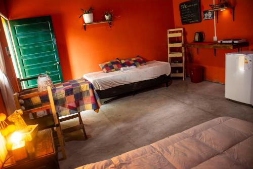 una camera da letto con pareti arancioni, un letto e un frigorifero di Tale Cabaña de campo a Huacalera