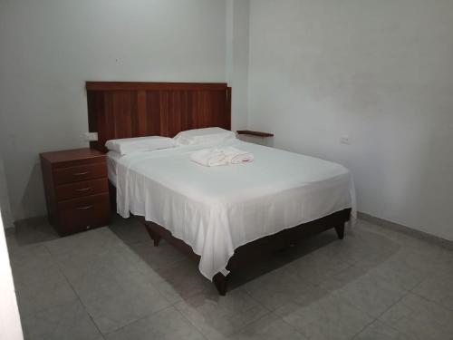 Una cama con sábanas blancas y un cabecero de madera. en Amaru Lodge, en Tingo María