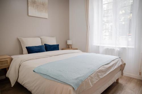 a white bedroom with a large bed with blue pillows at Saint-Fons centre appartement meublé in Saint-Fons