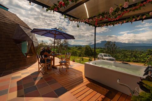 a man sitting at a table on a deck next to a hot tub at Prana Hills in Estación El Salto
