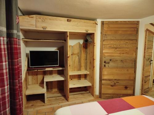 1 dormitorio con TV y armario de madera en Botton d'oro, en Campitello di Fassa