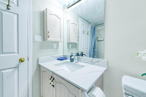 a white bathroom with a sink and a mirror at The Urban Family Pad in Toronto