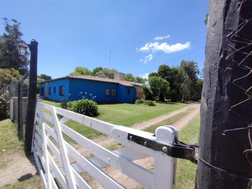 a white fence with a blue house in the background at La Posada del Mar in Miramar