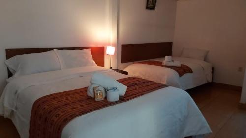 een hotelkamer met twee bedden met handdoeken erbovenop bij Casa Hospedaje Sunya in Cuzco